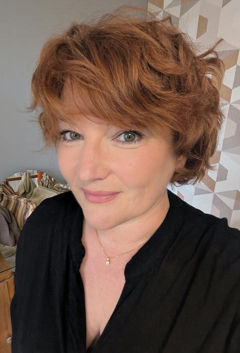 Portrait de Sophie Lenoble, esthéticienne, souriante, dans son institut devant le papier peint géométrique de l'accueil